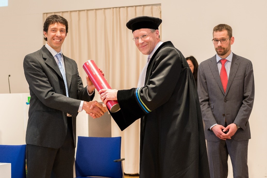 "Gerard hands over a PhD-diploma to Marcos Angelini, the first doctor delivered during his special professorship. Co-promotor Bas Kempen looks on"